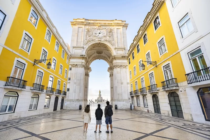 Rua Augusta Arch in Lisbon framed by yellow buildings and cobblestone streets.