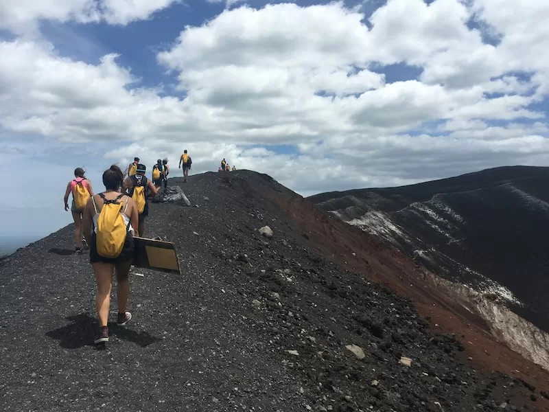 Group of hikers walking along a volcanic ridge in Nicaragua under a broad blue sky