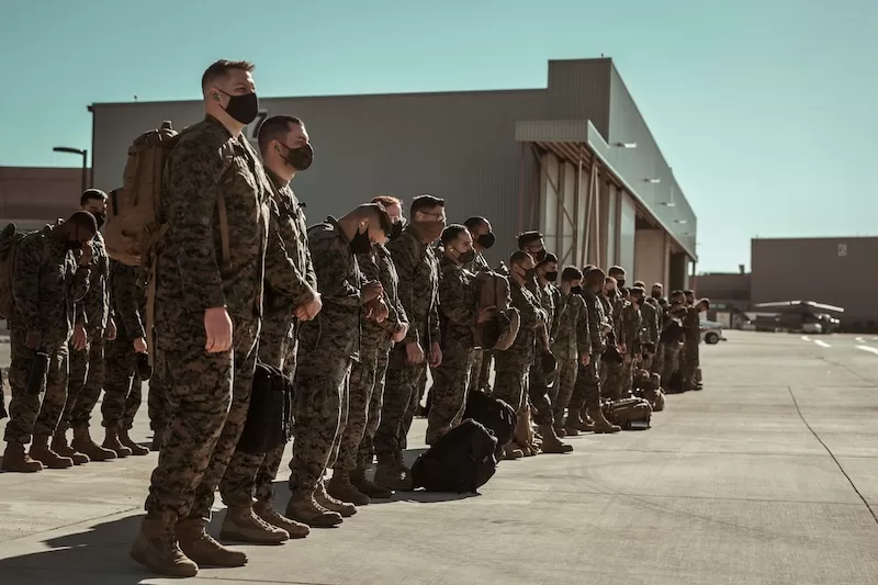 Military personnel lined up on an airfield, representing the rising operational cost of the Iran conflict