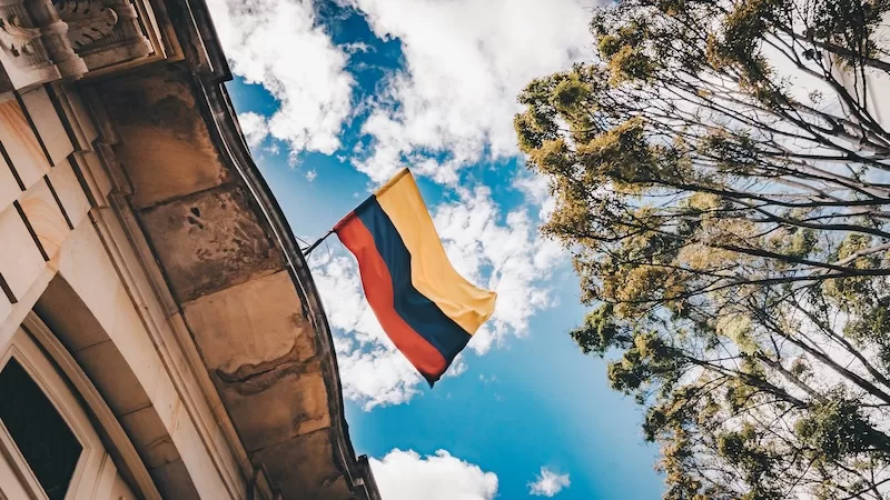 Colombian flag flying against a blue sky, representing citizenship and residency options in Latin America.