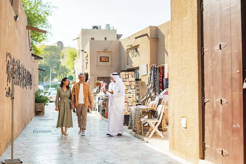 Couple walking with a local guide through a traditional market street in the Middle East
