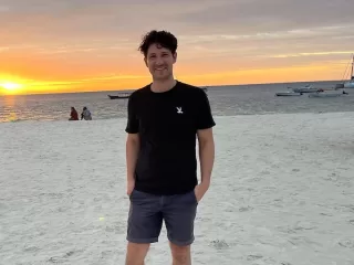 Christopher Nash standing on Kendwa Beach in Zanzibar at sunset.