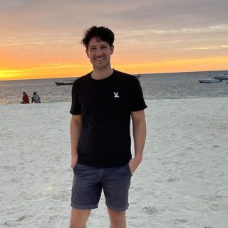 Christopher Nash standing on Kendwa Beach in Zanzibar at sunset.