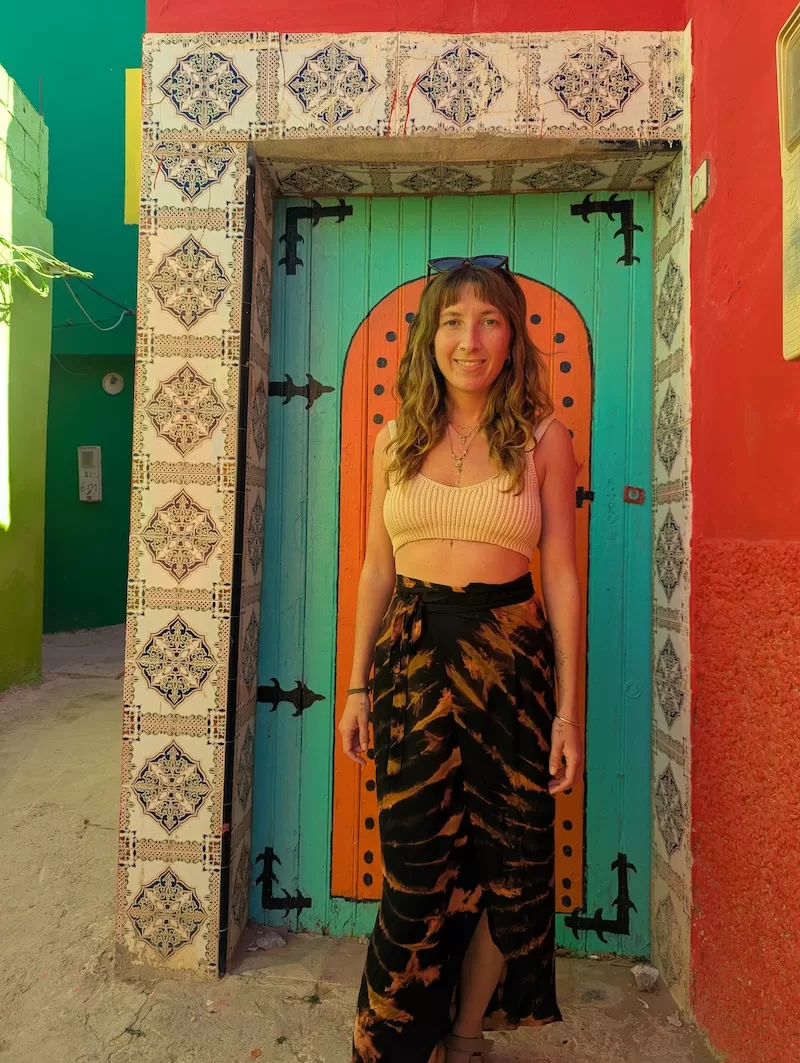 Woman standing in front of a colorful Moroccan doorway with patterned tiles