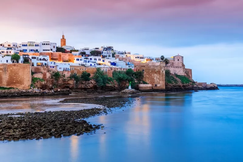Historic Moroccan city walls overlooking calm blue water