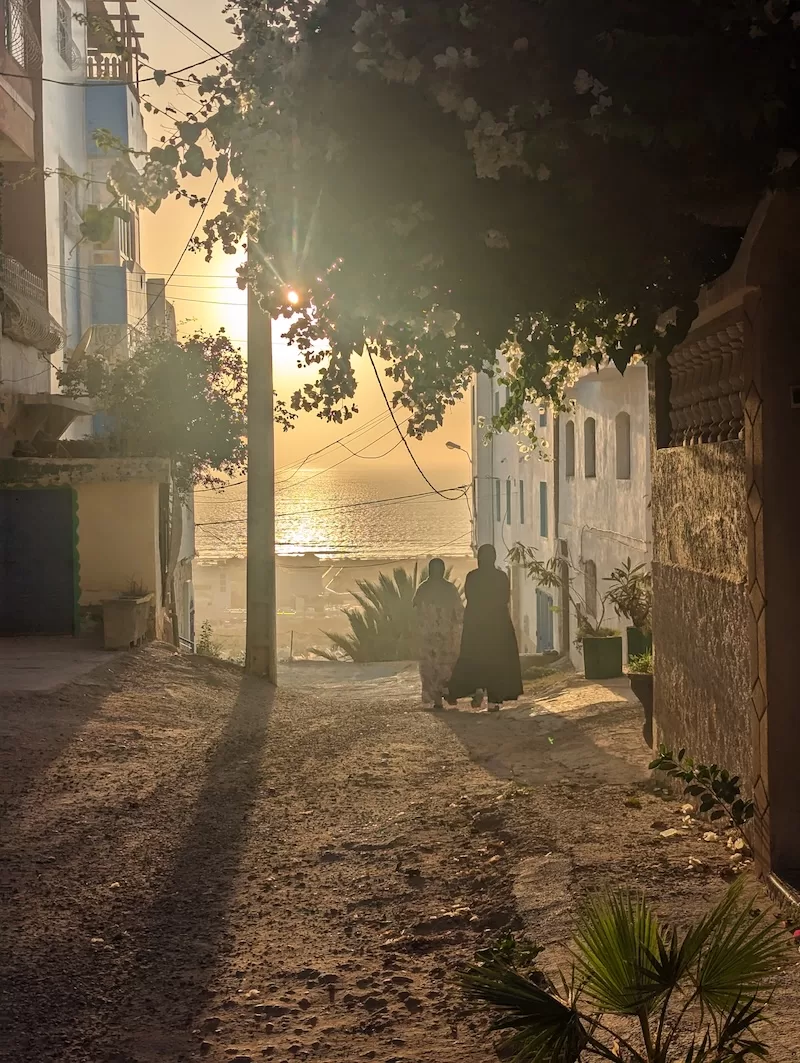 Sunset view down a narrow Moroccan street toward the ocean