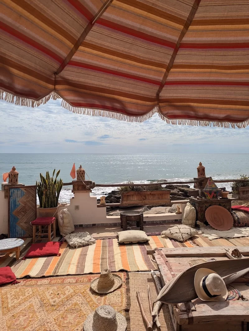 Moroccan terrace with rugs, cushions, and ocean views