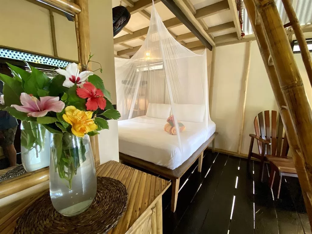 Caribbean resort bedroom with white mosquito-net bed and tropical flowers