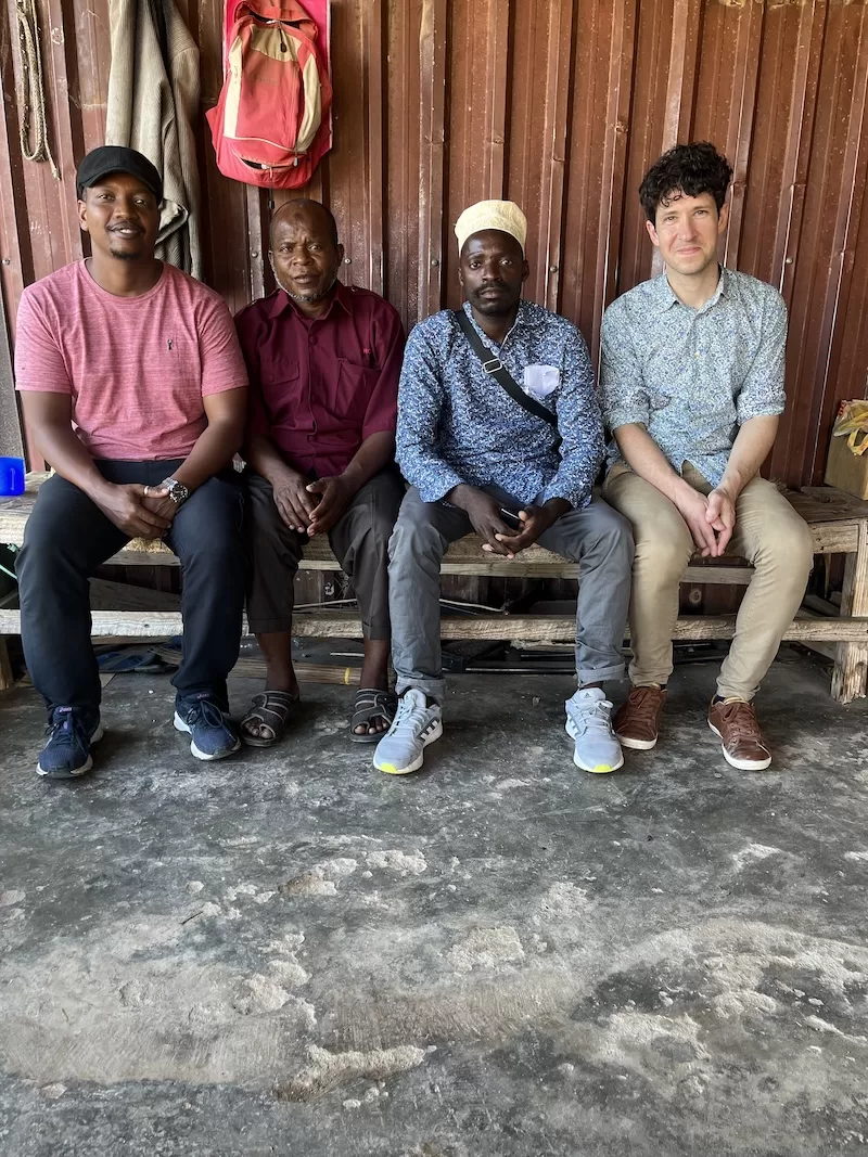 Christopher Nash seated with local men during a community conversation in Kendwa.