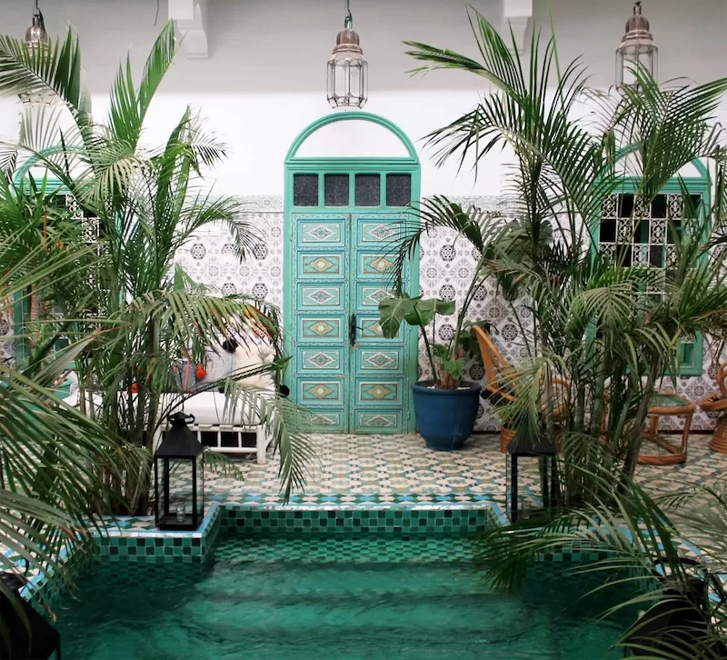 Traditional Moroccan riad courtyard with turquoise door and tiled pool