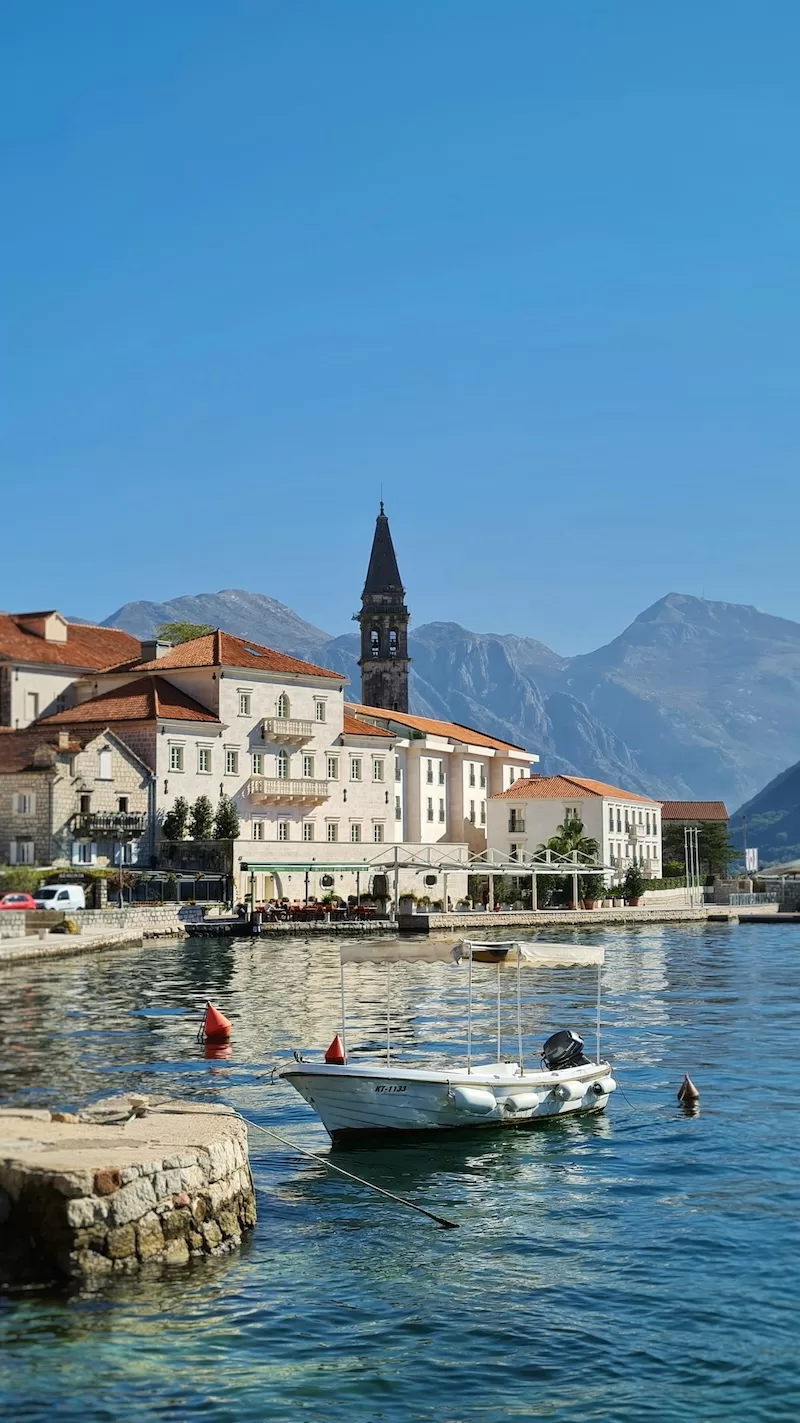 Boat moored in the Bay of Kotor with historic buildings and mountains in Montenegro