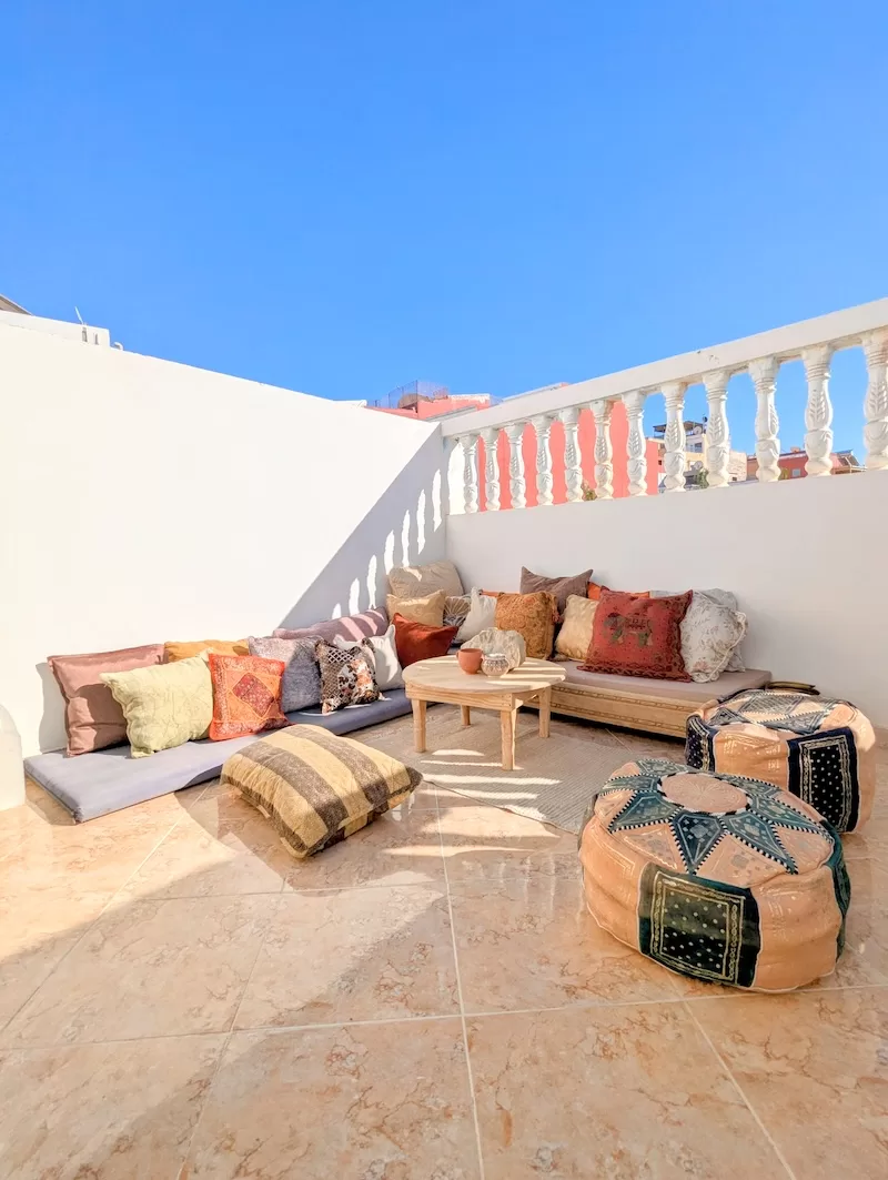 Bright Moroccan rooftop terrace with floor cushions and patterned poufs