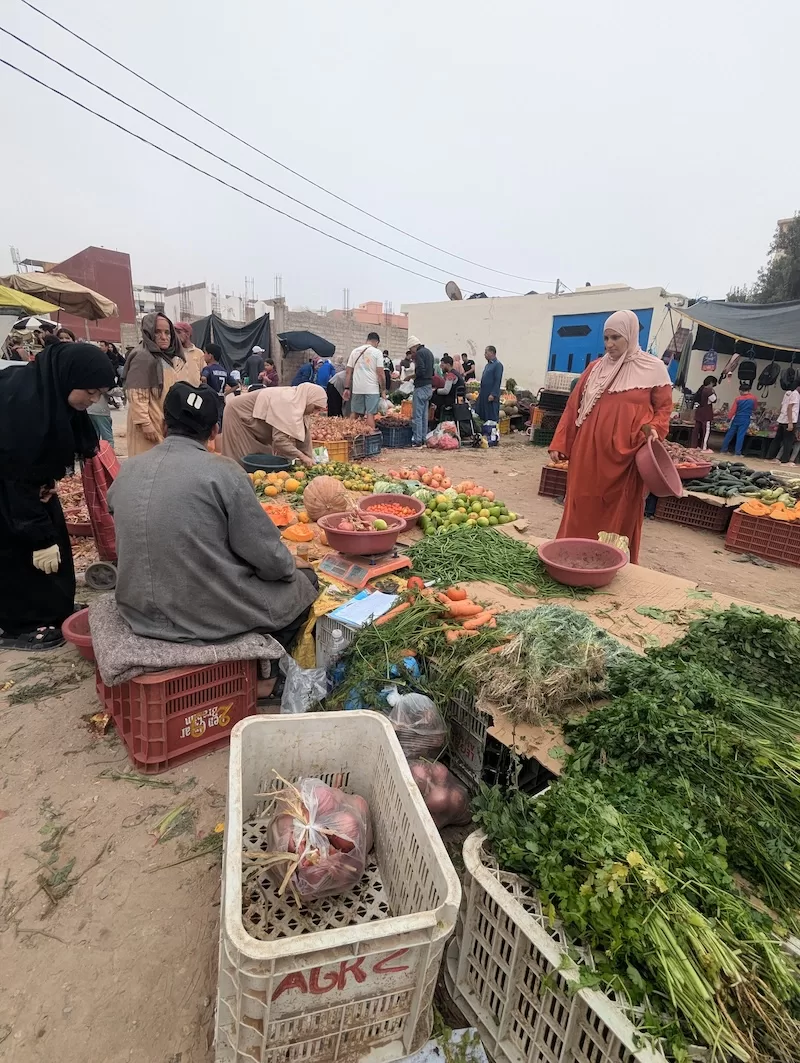 Outdoor Moroccan market with fresh vegetables and local shoppers