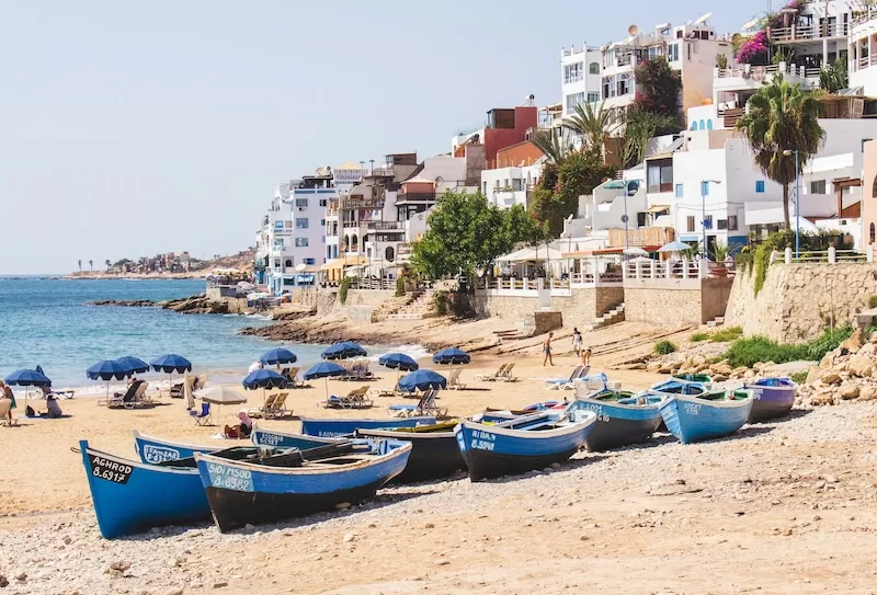 Moroccan beachfront with white buildings, fishing boats, and ocean views