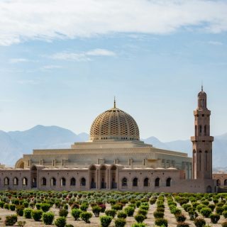 Qaboos Grand Mosque in Muscat Oman with mountains in the background