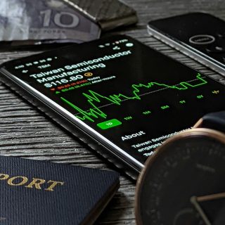 Smartphone showing an international semiconductor stock investment beside passports and cash