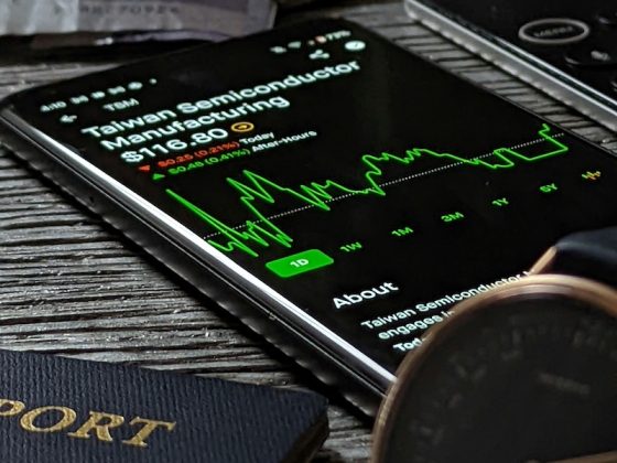 Smartphone showing an international semiconductor stock investment beside passports and cash