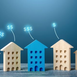 Wooden house models of increasing size with rising dollar signs, representing growing asset value