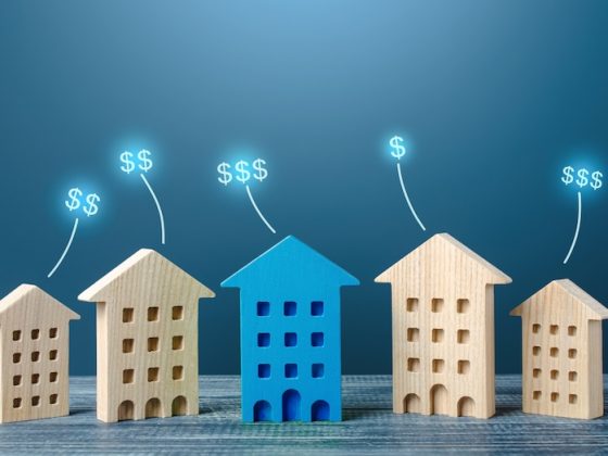Wooden house models of increasing size with rising dollar signs, representing growing asset value