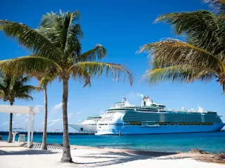 Cruise ship docked beside a Caribbean beach with palm trees