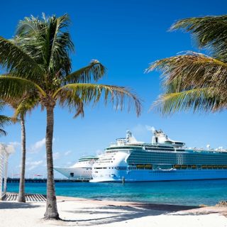 Cruise ship docked beside a Caribbean beach with palm trees