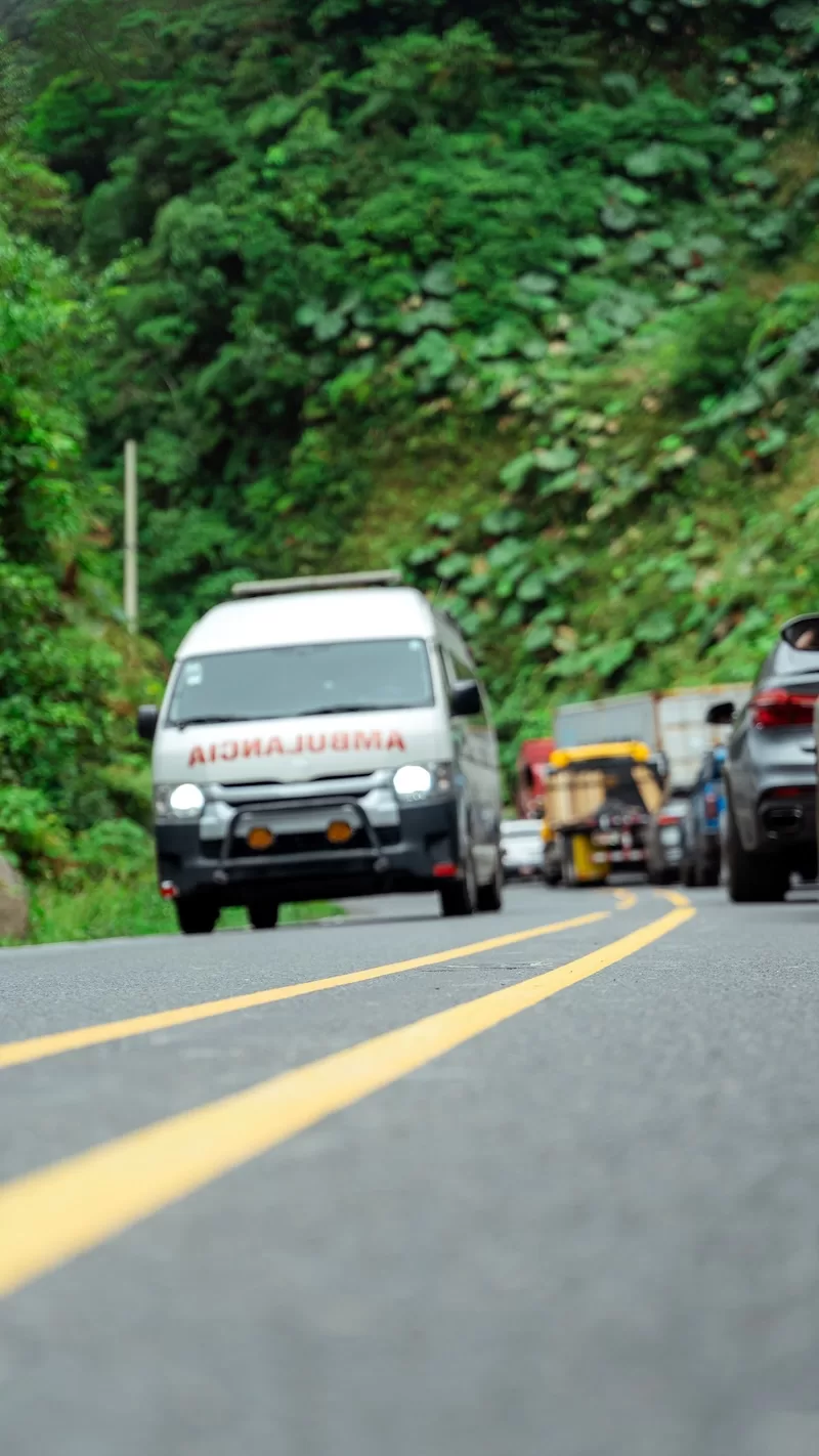 Ambulance driving on a winding road through green hills in Costa Rica