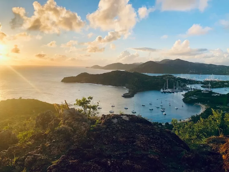 Caribbean island bay at sunset with boats and green hills