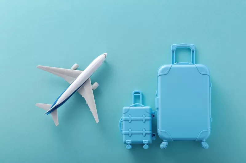 Toy airplane and stacked blue suitcases representing international travel and relocation