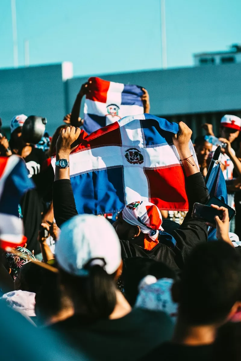 Crowd holding up Dominican Republic flags at an outdoor gathering