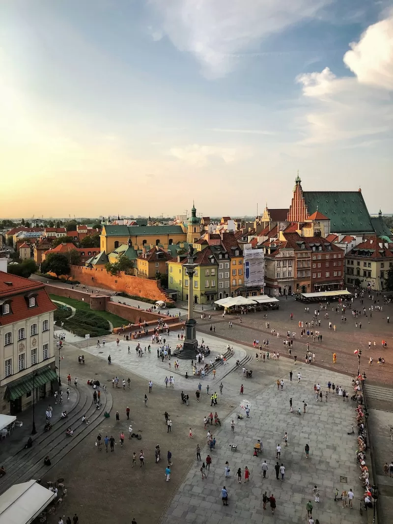 Aerial view of Warsaw's Castle Square with crowds gathered near the Sigismund's Column at sunset