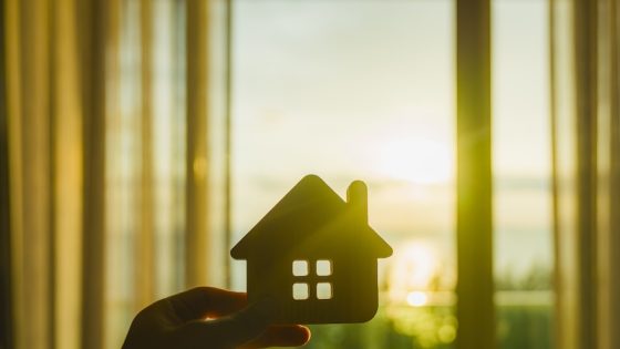 House-shaped cutout held against a bright window at sunset