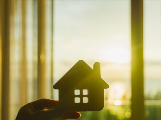 House-shaped cutout held against a bright window at sunset