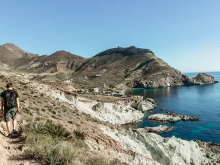 Hiker walking along a rugged coastal trail in Andalusia overlooking the Mediterranean Sea