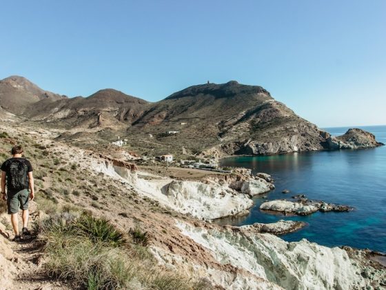 Hiker walking along a rugged coastal trail in Andalusia overlooking the Mediterranean Sea