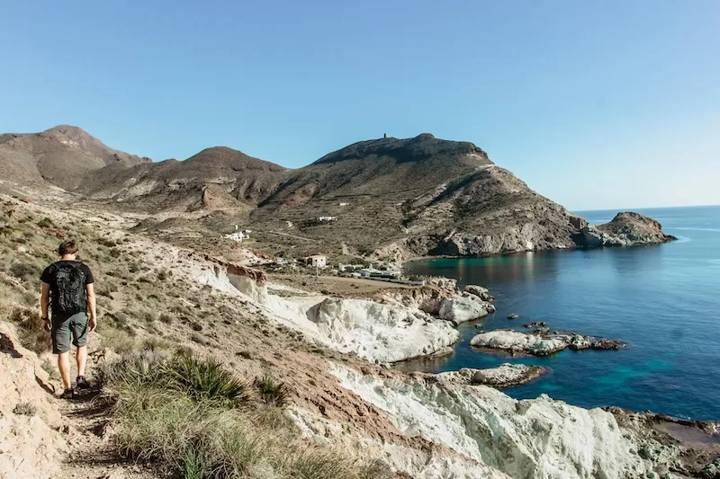Hiker walking along a rugged coastal trail in Andalusia overlooking the Mediterranean Sea