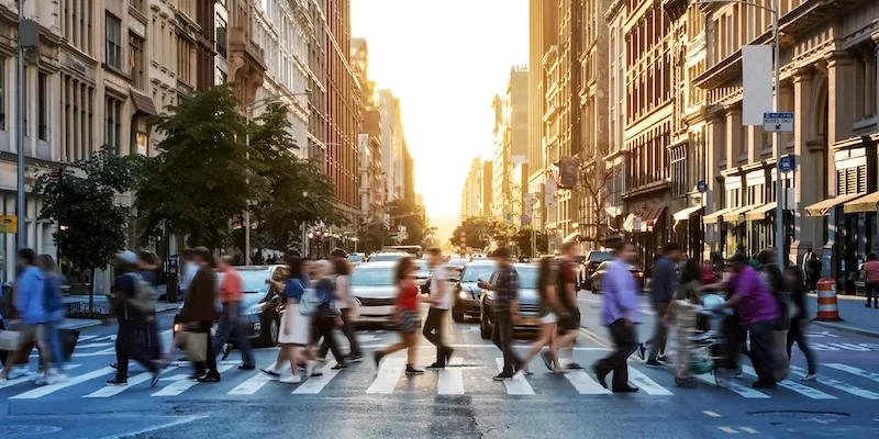 Blurred motion of pedestrians crossing a busy New York City street at sunset