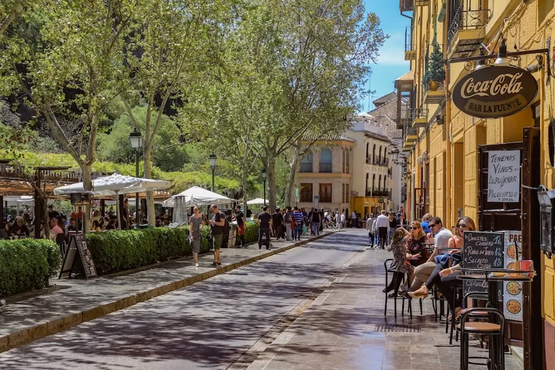 Tree-lined Andalusian street with outdoor cafés and pedestrians