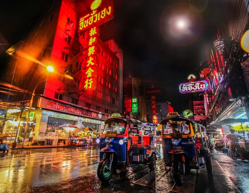 Tuk-tuks on a neon-lit street at night in Bangkok, Thailand