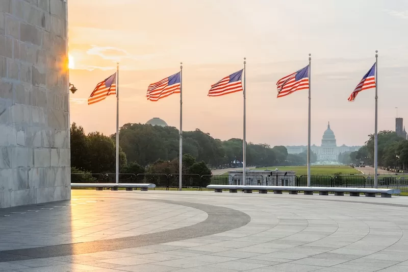 American flags flying at sunrise with the US Capitol dome in the background