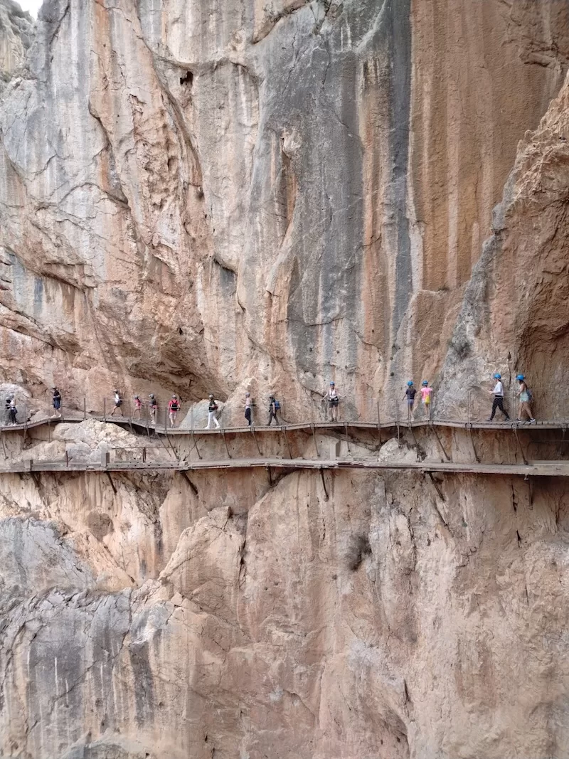 Visitors walking along a cliffside pathway through an Andalusian gorge