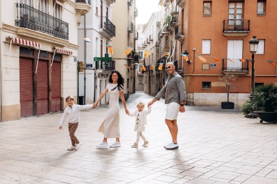 A family walking through a narrow street in Valencia's old town during a photo session, part of starting a business in Spain as an expat photographer.