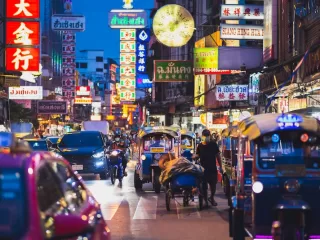Tuk tuks, taxis and neon signs crowd a Bangkok Chinatown street at night