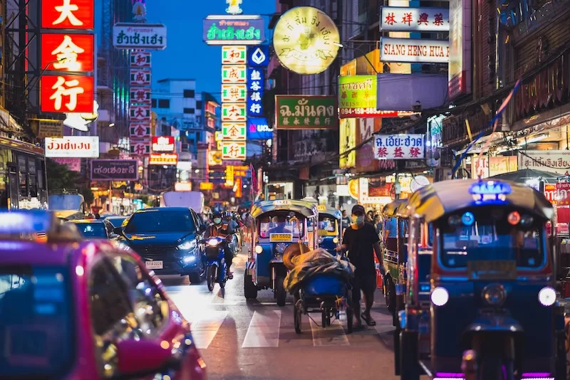 Tuk tuks, taxis and neon signs crowd a Bangkok Chinatown street at night