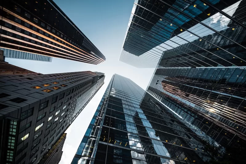Glass banking towers seen from the street, rising toward a clear sky.