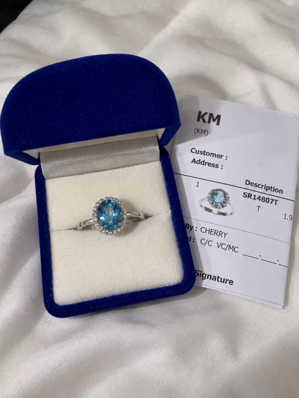 A blue topaz ring in its box beside the shop receipt from a Bangkok jewelry stop.