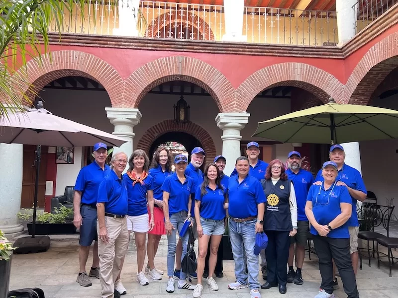 Volunteers and a local Rotary partner gather in a colonial courtyard before a distribution.