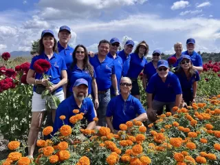 Chair the Love volunteers in blue polos gathered in a field of marigolds and celosia during a distribution trip