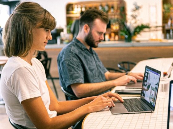 Two remote workers on laptops in a cafe, illustrating digital nomad visa options in 2026