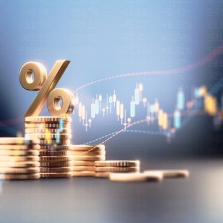 Stacks of gold coins under a percent sign against a rising market chart: the financial footing banking diversification protects