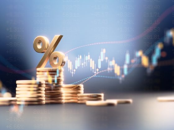 Stacks of gold coins under a percent sign against a rising market chart: the financial footing banking diversification protects